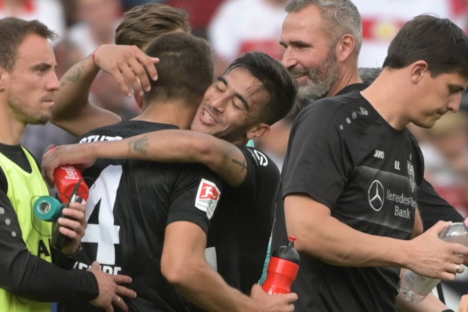 Nicolás González von Stuttgart (M) umarmt nach dem Sieg mit 2:3 gegen Regensburg seinen Teamkollegen Marc-Oliver Kempf. Dahinter beobachtet VfB-Coach Tim Walter das Geschehen mit voller Zufriedenheit.