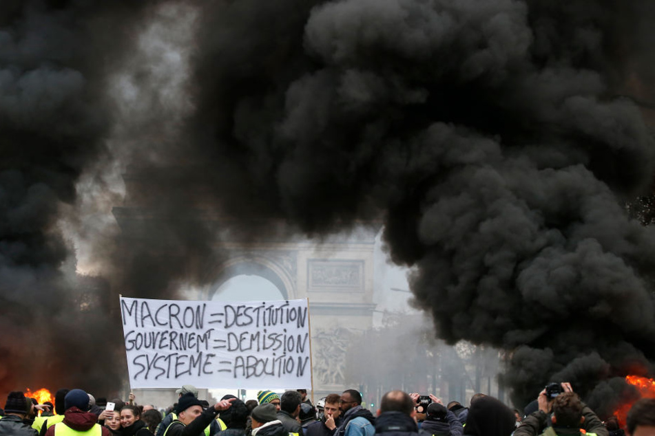 Demonstranten halten während einer Demonstration gegen die Erhöhung der Kraftstoffsteuern ein Banner mit der Aufschrift "Makron = Entlassung, Regierung = Rücktritt, System = Abschaffung",