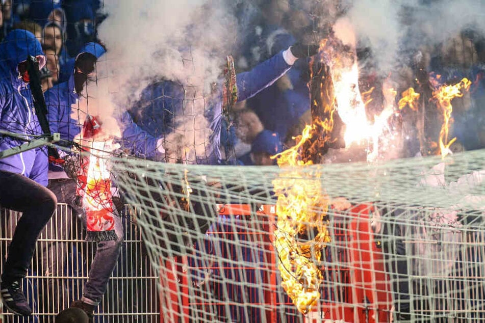 Maskierte Herthafans zünden Union T-Shirts an.