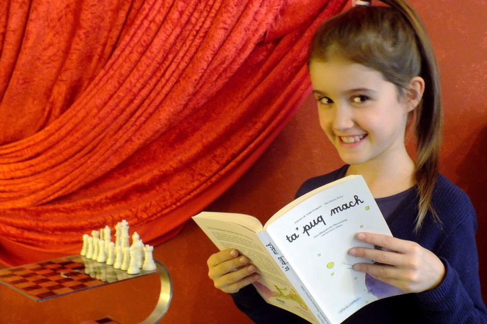 Die siebenjährige Aurélie Litaer hält das Buch „Der Kleine Prinz“ auf Klingonisch in den Händen.