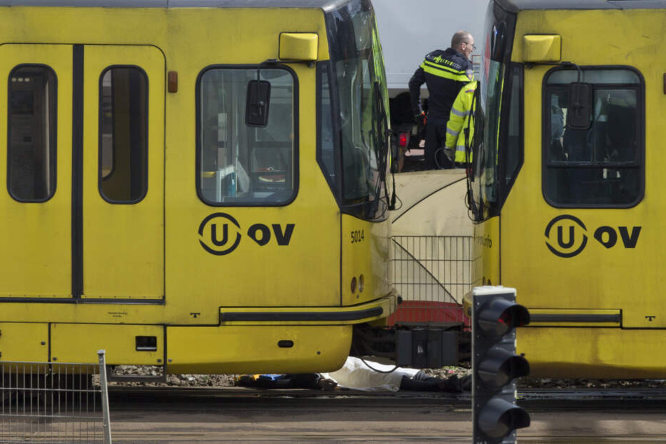 Abgedeckt mit einem Tuch liegt ein Körper an einem Straßenbahnwagen.