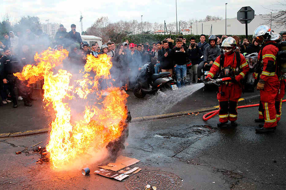 Feuerwehrmänner löschen eine brennende Mülltonne auf einem Schulhof im französischen Bayonne.