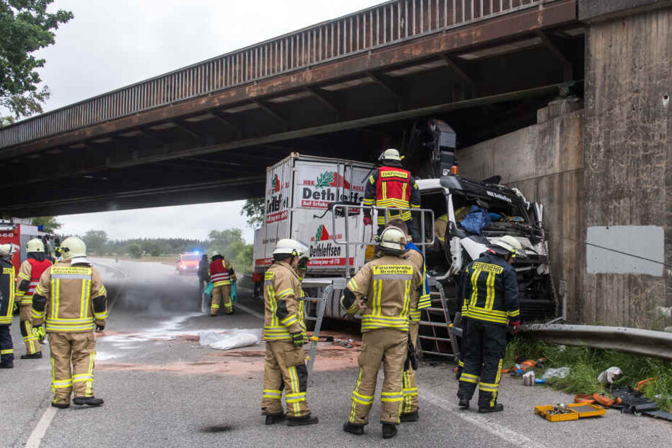Feuerwehrmänner arbeiten an einem Lastwagen, der eine Eisenbahnbrücke gerammt hat