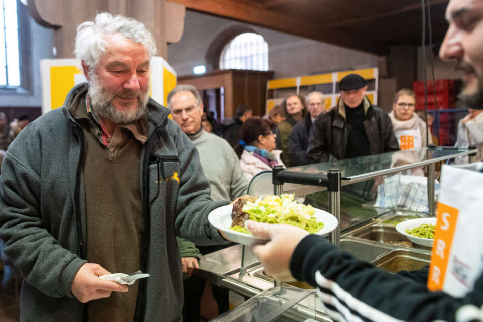 Marek nimmt sich einen Teller mit Essen in der Versperkirche.