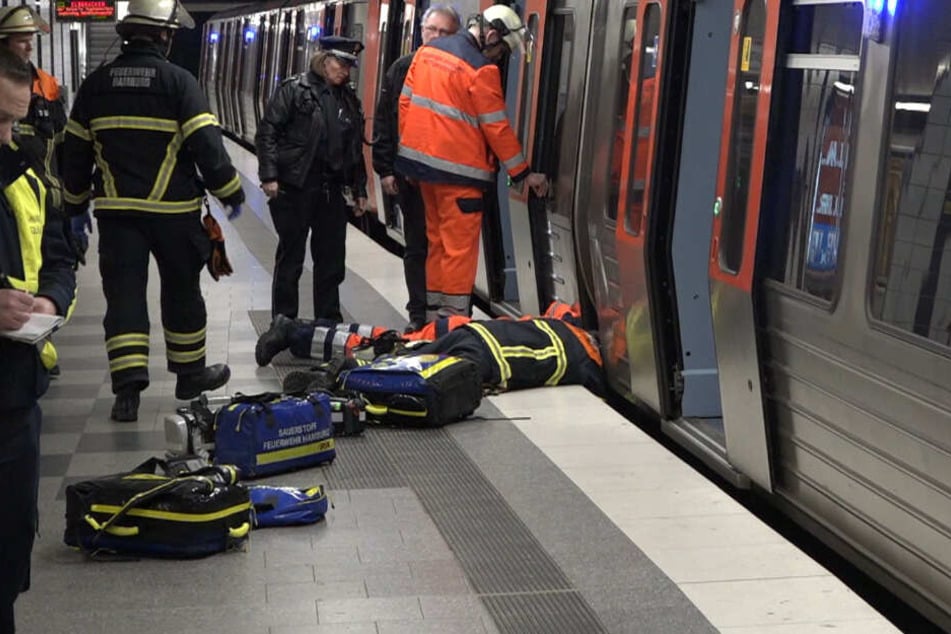 Ein Feuerwehrmann liegt am Boden und spricht mit dem Jugendlichen, der ins Gleisbett gefallen war und sich in einen Zwischenraum retten konnte.