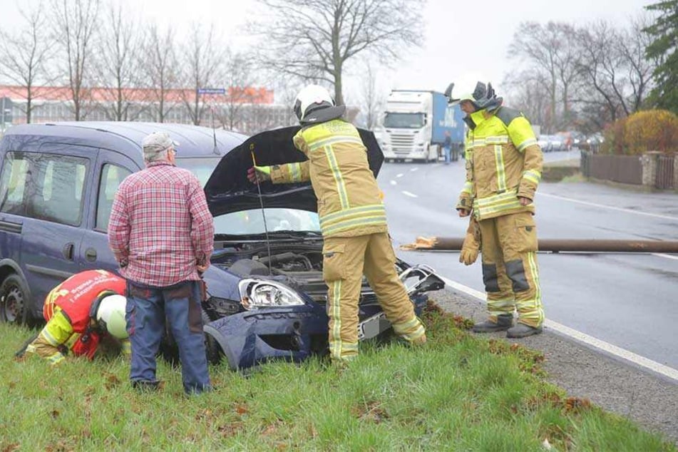 Kameraden der Feuerwehr stehen an dem Unfallauto und prüfen, ob Betriebsstoffe auslaufen.