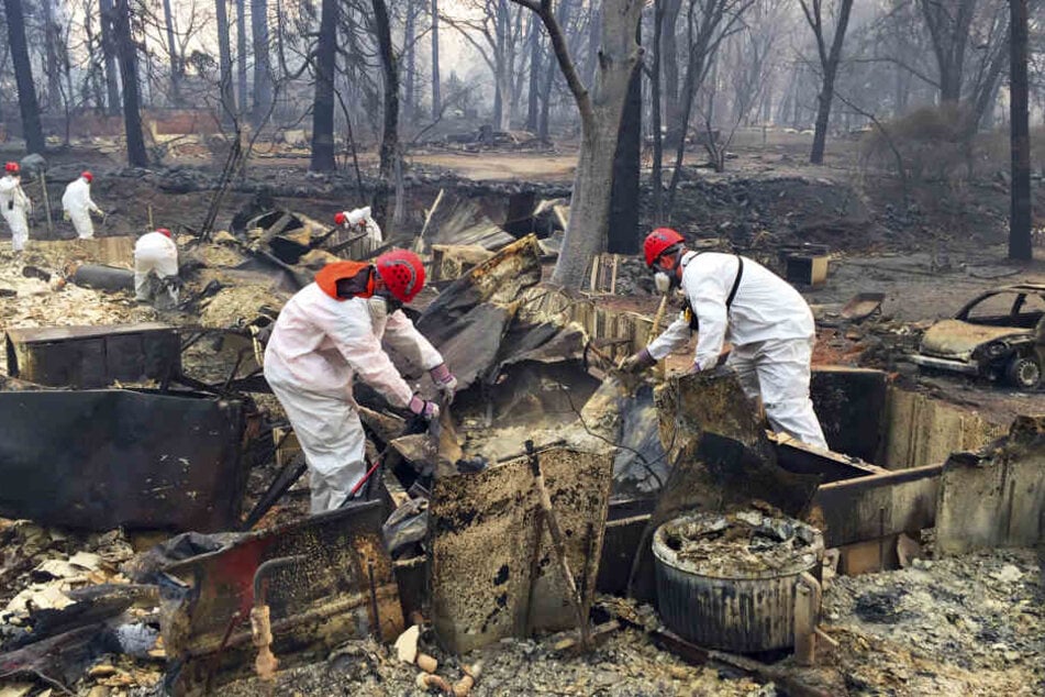 Freiwillige Rettungskräfte suchen in den Trümmern von Häusern, die dem "Camp"-Feuer zum Opfer gefallen sind, nach menschlichen Überresten.