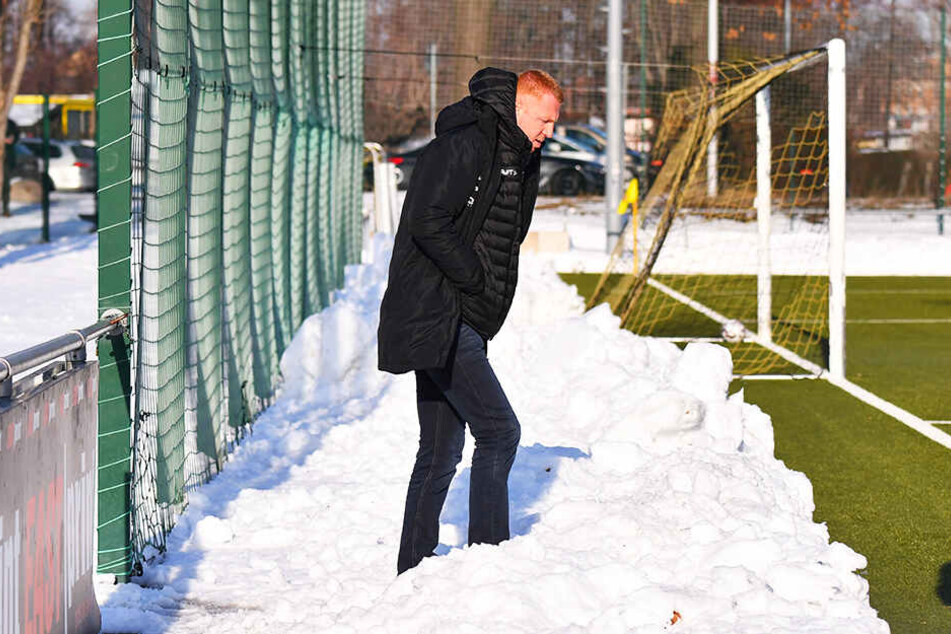 Er steht hier zwar nicht im Regen, aber im tiefen Schnee! Um aufs Spielfeld zu gelangen, muss Dynamos Trainer Maik Walpurgis einen dicken Schneehaufen überwinden.