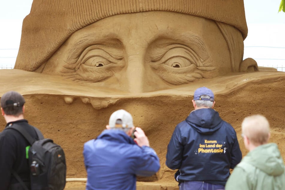 Besucher betrachten die Skulptur "Auf der Suche nach Atlantis" am Passagierkai in Warnemünde.