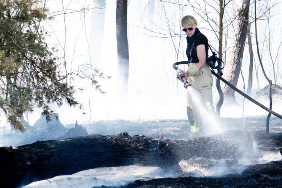 Eine Feuerwehrfrau löscht einen Waldbrand.