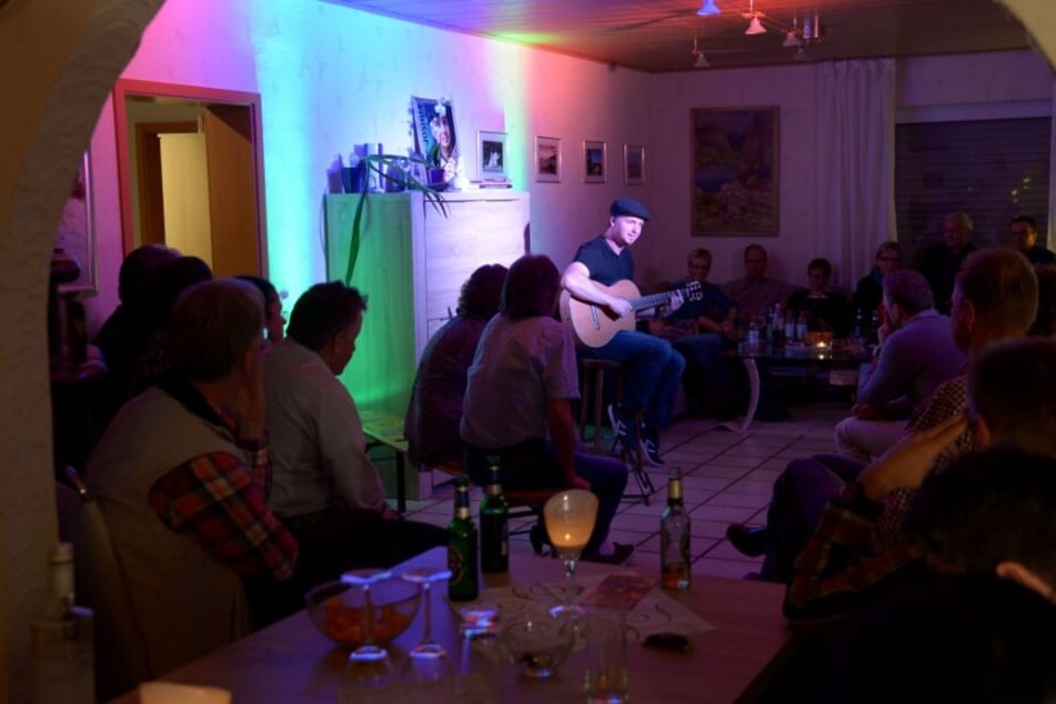 Der Musiker Joshua Carson tritt in einem fremden Wohnzimmer auf.