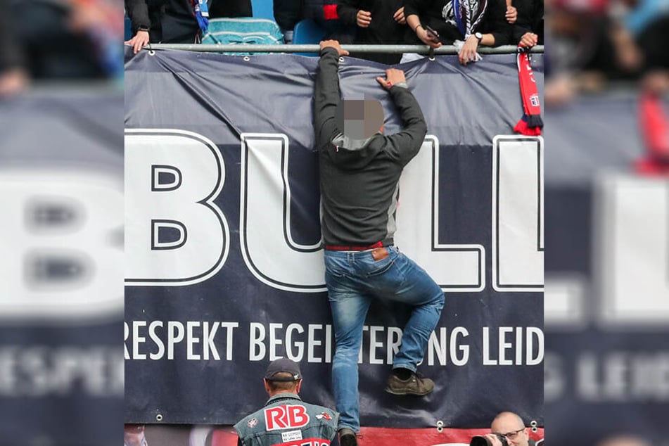 Nach dem Abpfiff kletterte ein RB-Fan über die Brüstung und sprang in die Tiefe. Unten wartet Ralf Rangnick in seiner Weste, mit dem der Anhänger ein Foto machen will.