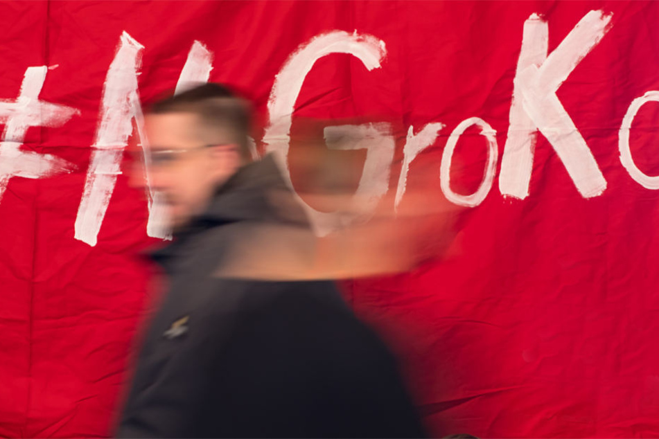 Politisch Interessierte laufen bei einer Veranstaltung "Groko oder NoGroko" vor einem Plakat mit der Aufschrift "#NoGroKo".