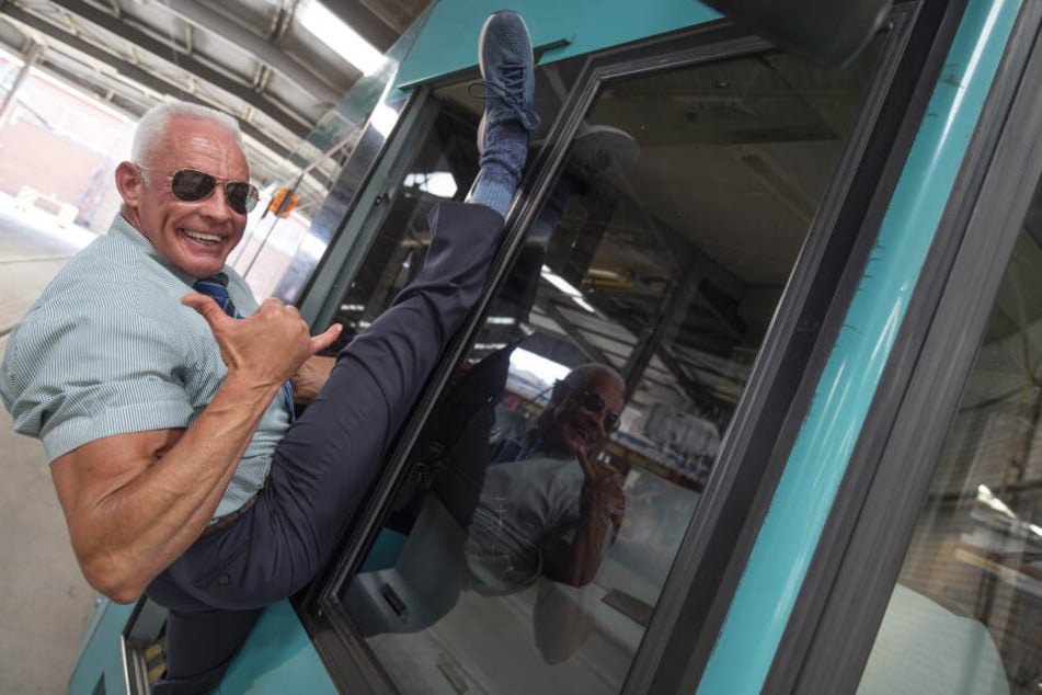 Peter Wirth (57) stretcht sich an einer Straßenbahn.