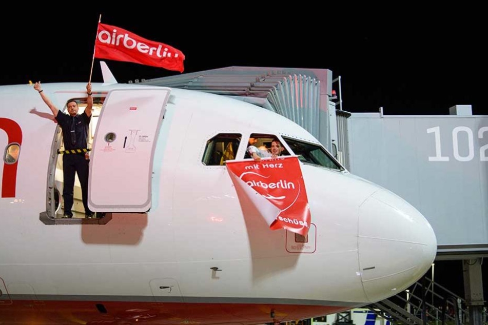 Mitarbeiter von Air Berlin schwenken vor dem letzten Flug der Airline am 27.10.2017 auf dem Vorfeld vom Flughafen in München eine Air-Berlin-Fahne.