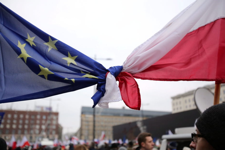 Flaggen der EU und Polens sind bei einer Demonstration in Warschau zusammengeknotet.