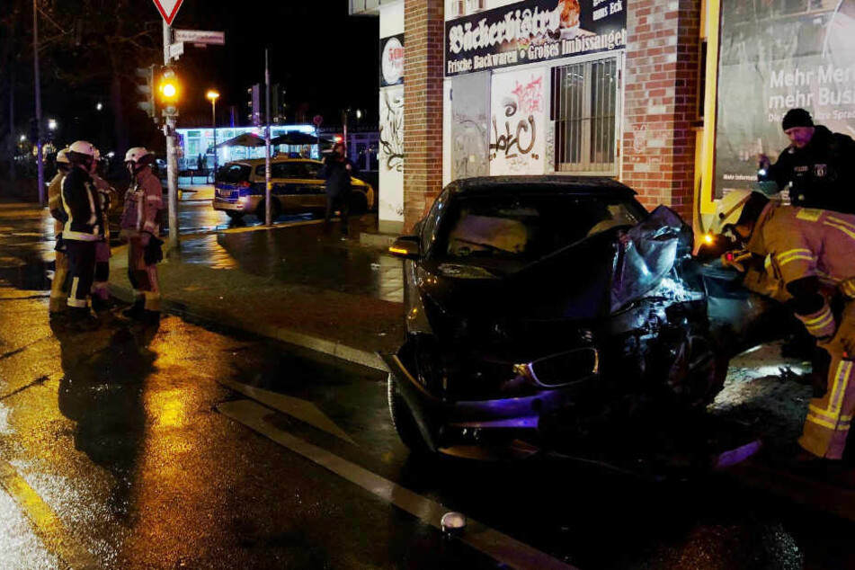 Ein Feuerwehrmann und ein Polizisten betrachten das Unfallauto.