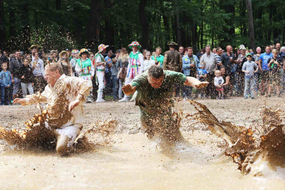 Skurriler Pfingstbrauch: Männer springen in Hergisdorf bei Lutherstadt Eisleben (Sachsen-Anhalt) immer wieder in Schlammkuhle.