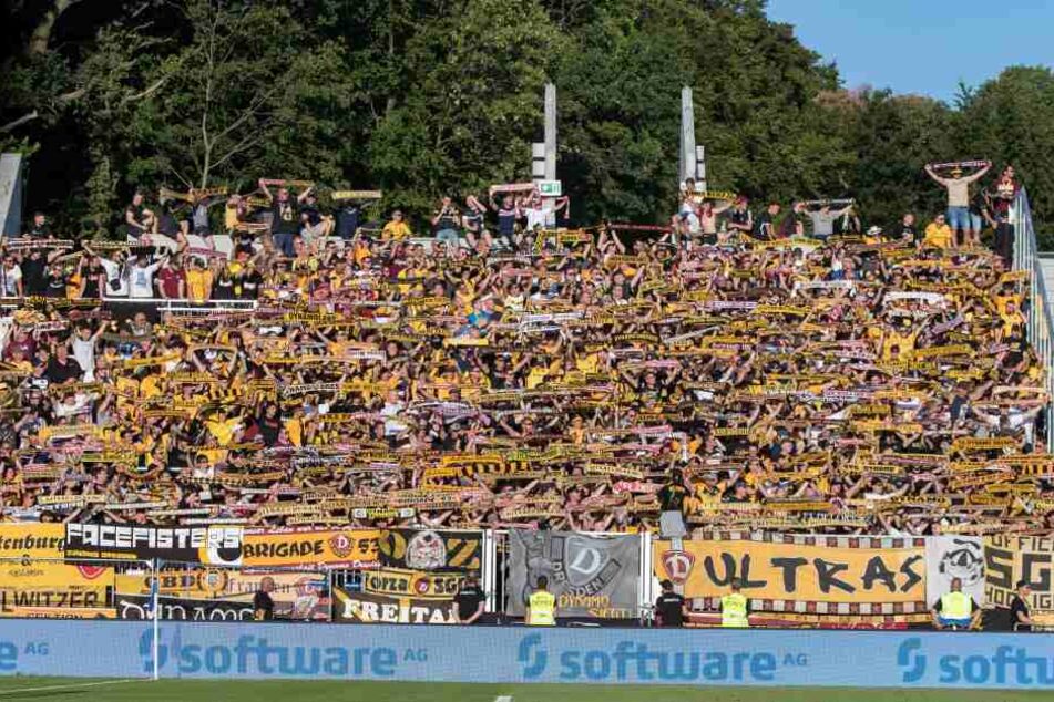 Die Fankurve beim Spiel von Dynamo in Darmstadt. Man sieht im Hintergrund, dass einige Fans auf der Mauer sitzen und stehen.