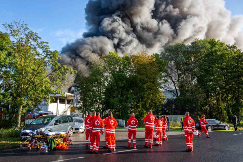 Rettungskräfte stehen bereit vor der in Brand stehenden Anlage.