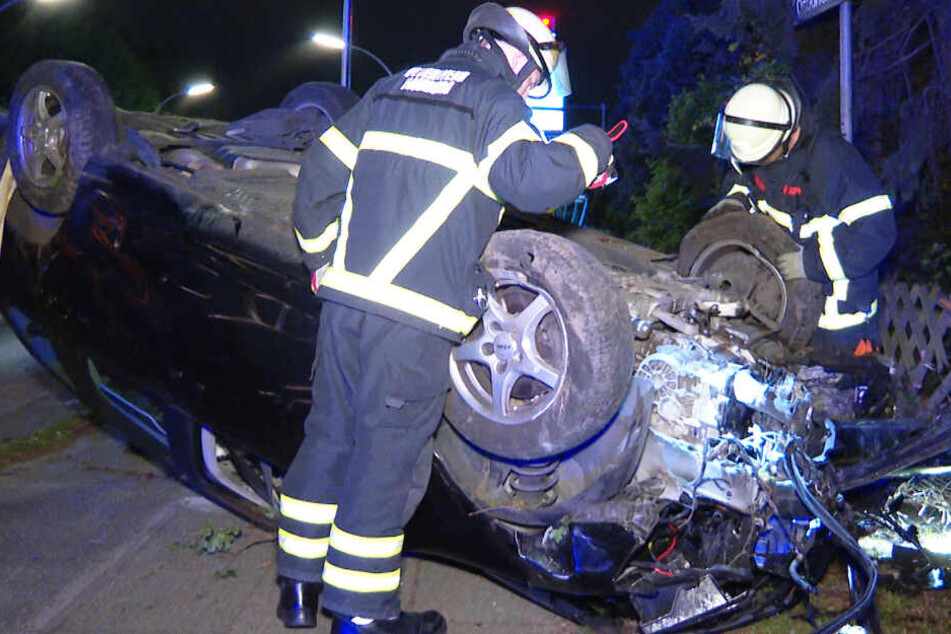 Feuerwehrleute begutachten das zerstörte Auto.