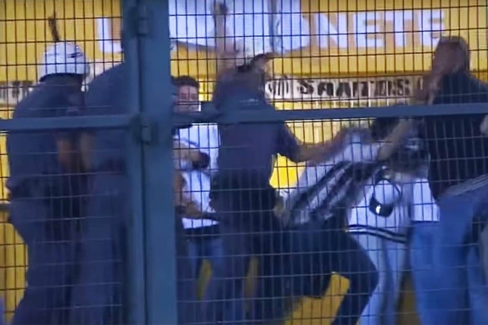 Polizisten dreschen auf Santos-Anhänger ein.