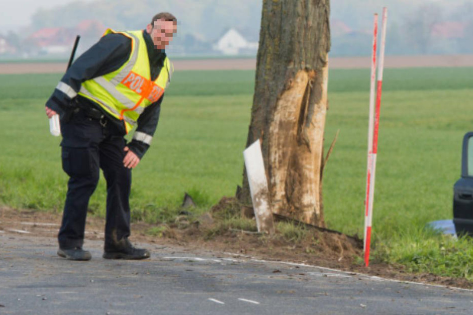 Ein Polizist beim Vermessen der Unfallstelle an dem Baum gegen den das Auto prallte. (Symbolbild)
