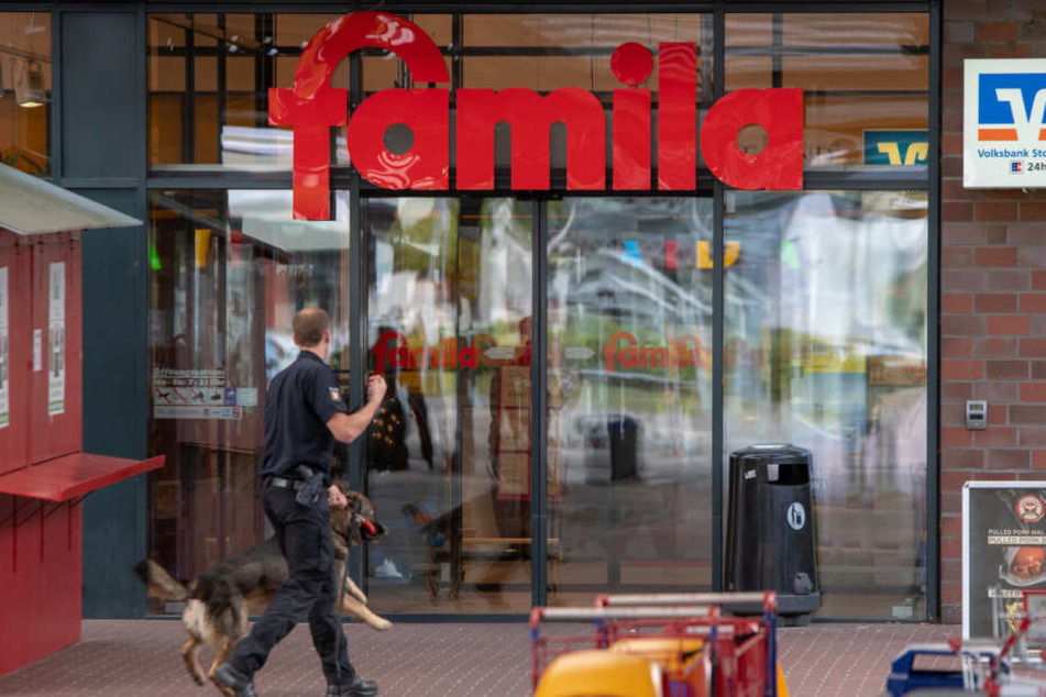 Ein Polizist geht mit einem Bombenspürhund in den Famila-Supermarkt in Reinbek bei Hamburg.