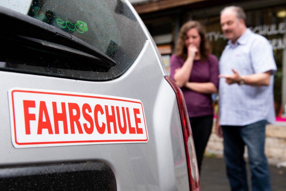 Ein Fahrlehrer erläutert einer Schülerin vor der Fahrt am Auto technische Details. Der Praxis-Teil liegt den Sachsen besser als die Theorie.