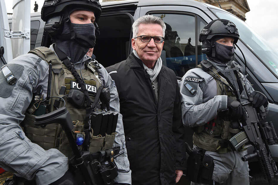 Bundesinnenminister Thomas de Maiziére zwischen schwer bewaffneten Polizisten in Potsdam.