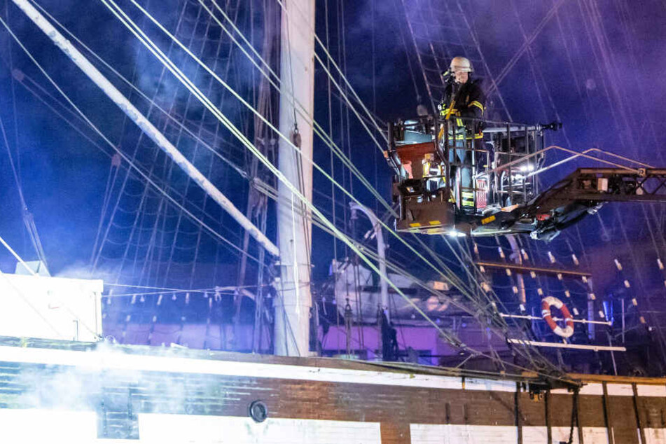 Ein Feuerwehrmann ist auf dem Leiterwagen im Einsatz, um den Brand auf dem Schiff zu löschen.