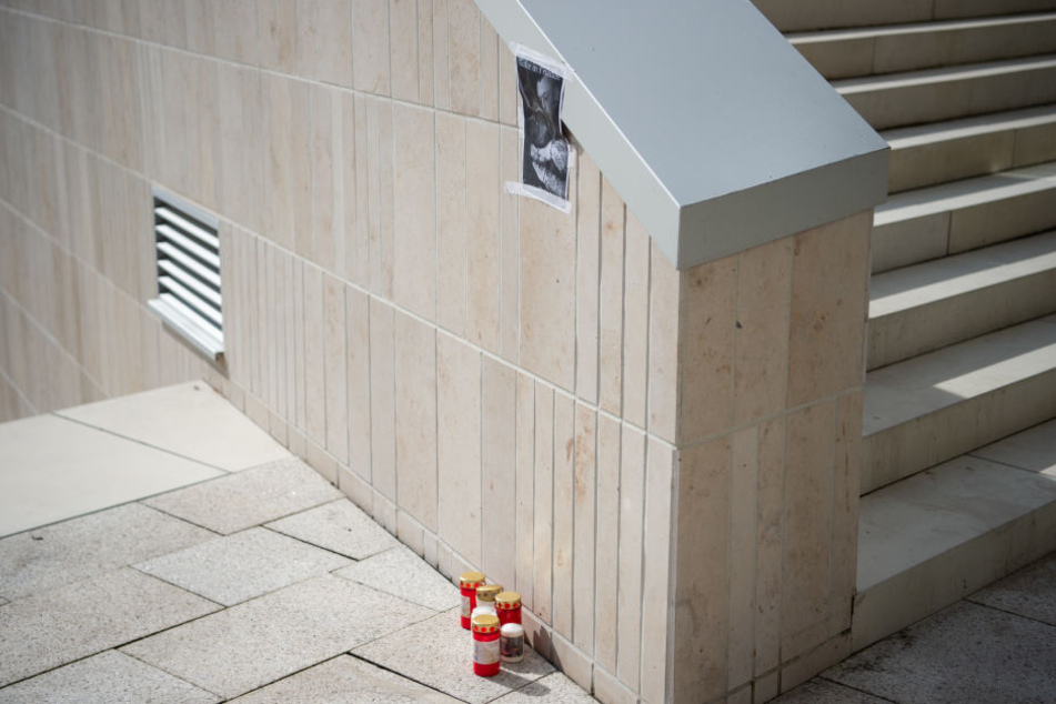 An einer Treppe stehen Kerzen unter einem Foto des Opfers.