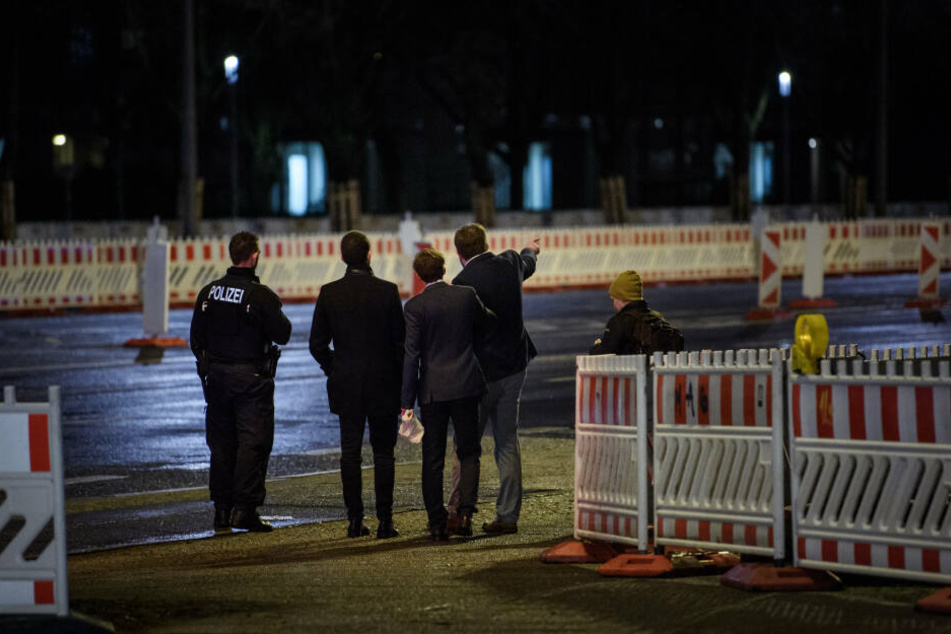 Vier Mitglieder der Jugendorganisation der Alternative für Deutschland, der Junge Alternative für Deutschland, stehen mit einem Polizisten auf dem Gehweg vor dem Kino International.