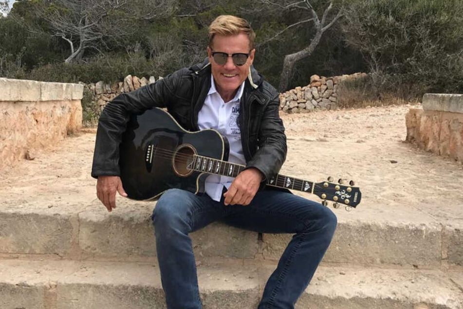 Dieter Bohlen sitzt mit einer Gitarre auf einer Treppe.