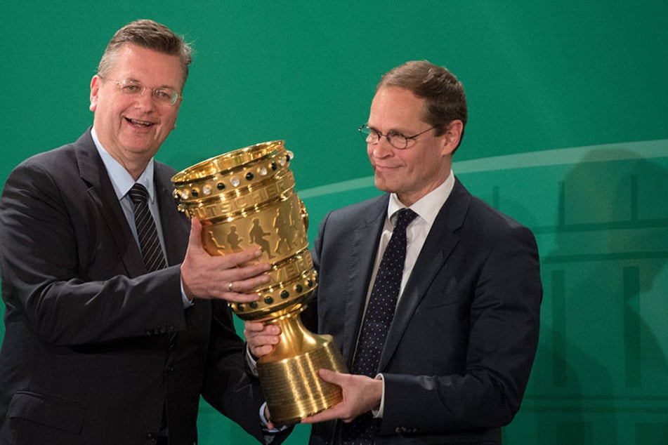 DFB-Präsident Reinhard Grindel (l.) übergibt während der traditionellen Übergabe des DFB-Pokals in Berlin die Trophäe an den Regierenden Bürgermeister der Hauptstadt, Michael Müller (SPD).