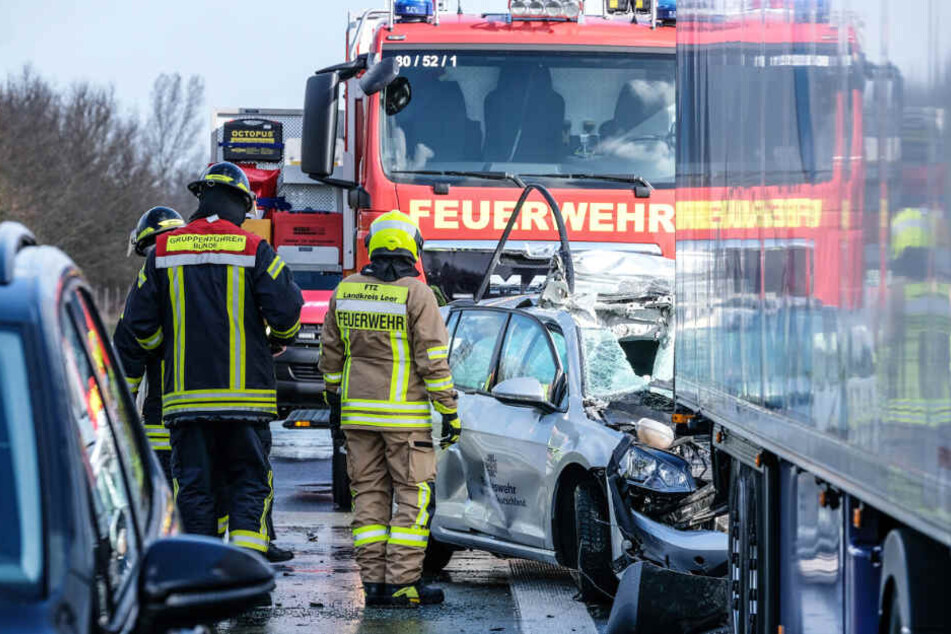 Feuerwehrleute sind an der Unfallstelle auf der A31 im Einsatz. Ein Auto der Bundeswehr geriet unter einen Lastwagen.