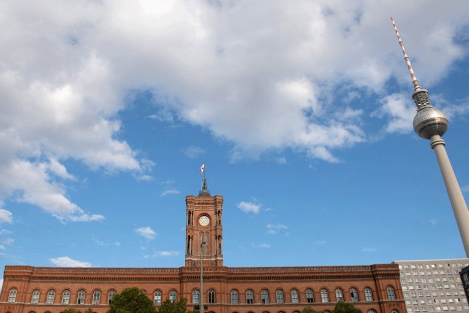 Rotes Rathaus und Fernsehturm werden von einem wolkigen Himmel überspannt.