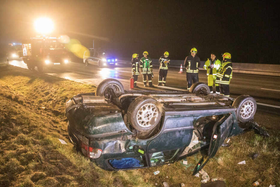 Einsatzkräfte stehen vor dem Fahrzeugwrack auf der A7.