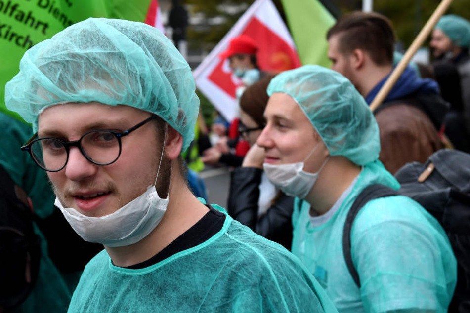Mitarbeiter der Uniklinik demonstrieren in Düsseldorf in Klinikkleidung. (Archivbild)