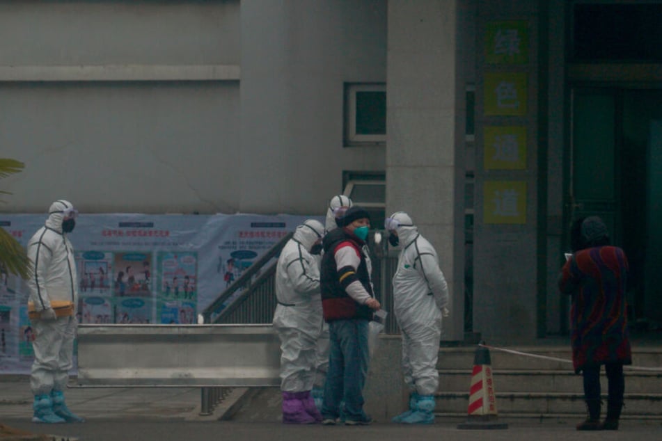 Mitarbeiter in Schutzanzügen stehen vor dem Wuhan Medical Treatment Center, in dem ein Patient mit Verdacht auf den neuartigen Corona-Virus behandelt wurde.