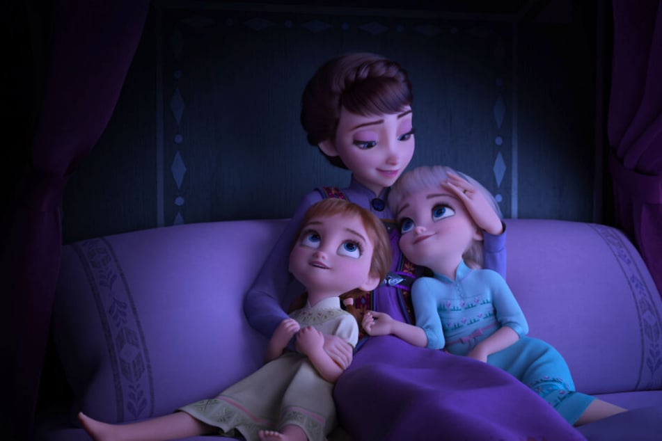 Königin Iduna (M.) erzählt ihren Töchtern Elsa (r.) und Anna eine Geschichte und singt für sie.