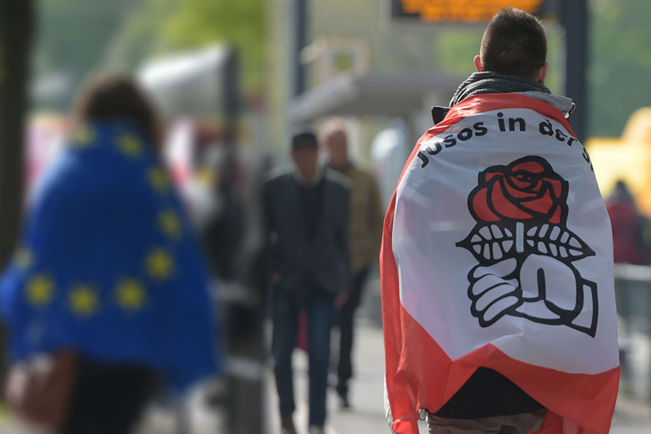 Ein Jungsozialist, kurz Juso, mit der Fahne der Nachwuchsorganisation bei einer Demo. Dass die Jusos nicht immer mit der SPD einer Meinung sind, wird bei der Linksextremismus-Debatte in Leipzig deutlich (Symbolbild).