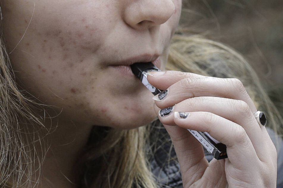 Eine Gymnasiastin verwendet ein Vaping-Gerät in der Nähe eines Schulgeländes.