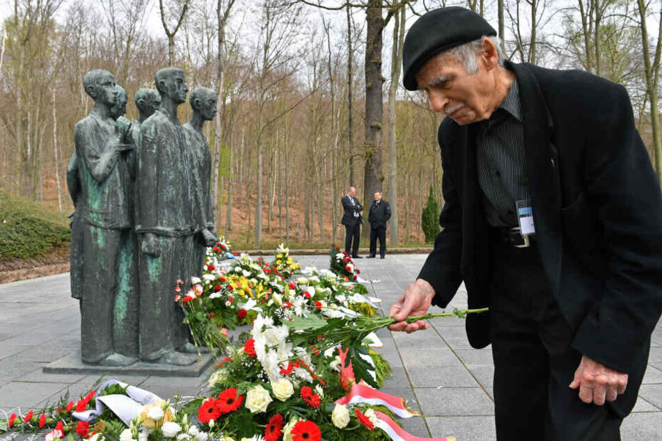 Vor dem Krematorium legt der früherer Häftling Pierre Berg aus Frankreich Blumen nieder.