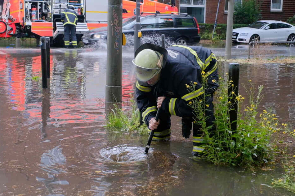 Ein Feuerwehrmann kämpft gegen die Wassermassen an einer Kreuzung.