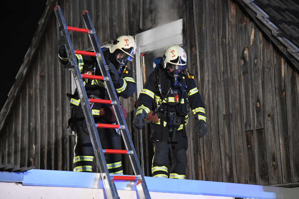 Feuerwehrleute mit Atemgerät kommen betreten das Dach des Hauses.