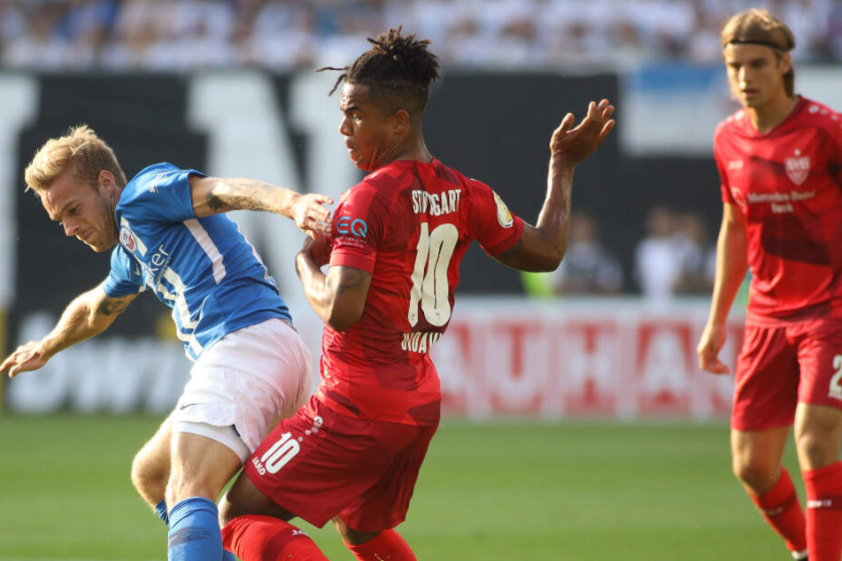 Rostocks Nils Butzen (l) kämpft mit Stuttgarts Daniel Didavi (M) um den Ball.