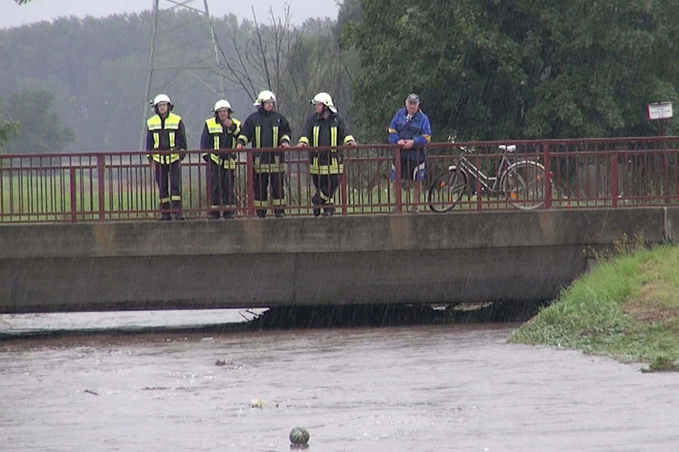 Kameraden der Feuerwehr schauen besorgt auf die Holtemme. Innerhalb weniger Stunden stieg das Wasser gefährlich an.