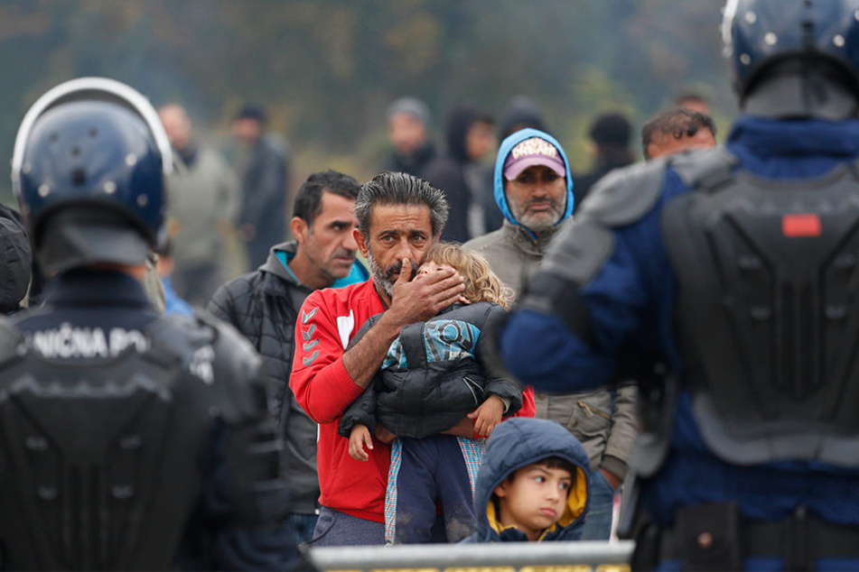 Ein Migrant hält ein Kind vor einer Polizeiabsperrung am Grenzübergang von Maljevac zwischen Bosnien-Herzegowina und Kroatien.