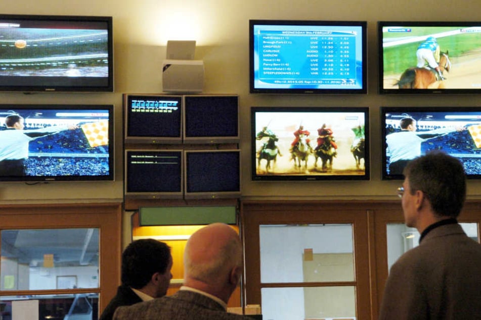 In einem Wettlokal verfolgen Besucher Sportwettkämpfe auf den Monitoren (Symbolbild)